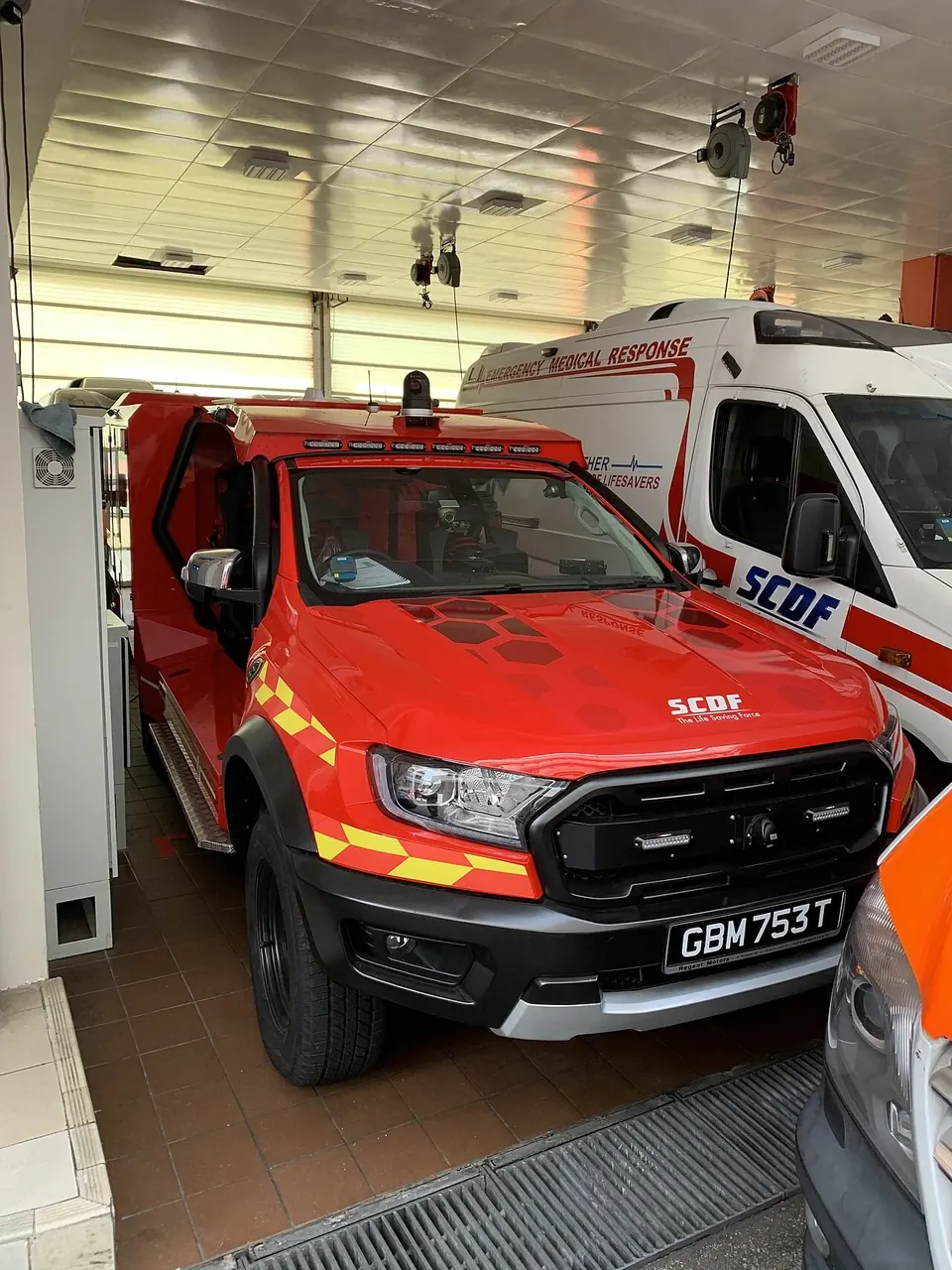 A red emergency pickup with a closed cab stands inside a vehicle bay.