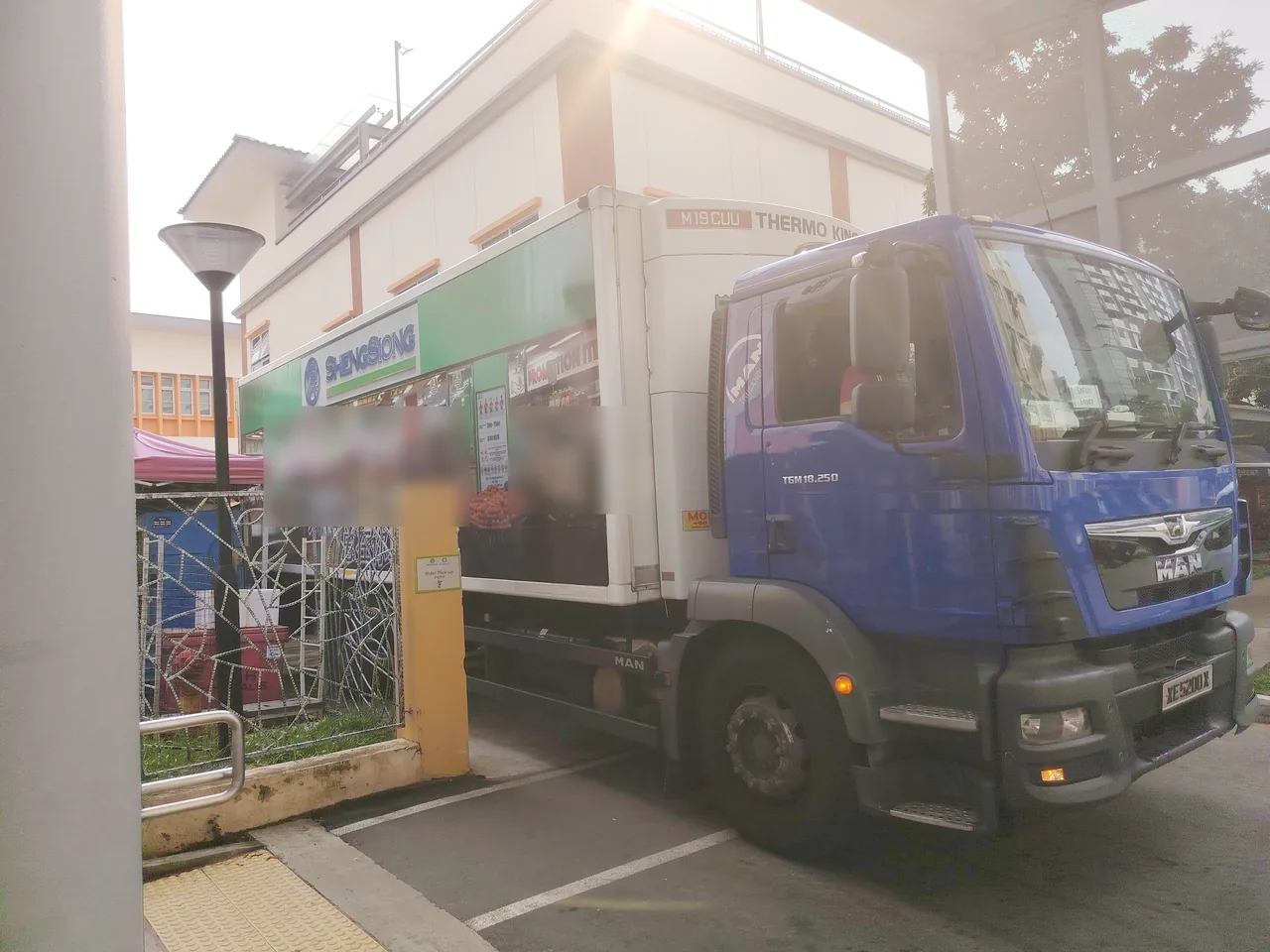 Refrigerated truck — a blue lorry with a white insulated box and a Thermo King cooling unit at a supermarket loading bay.