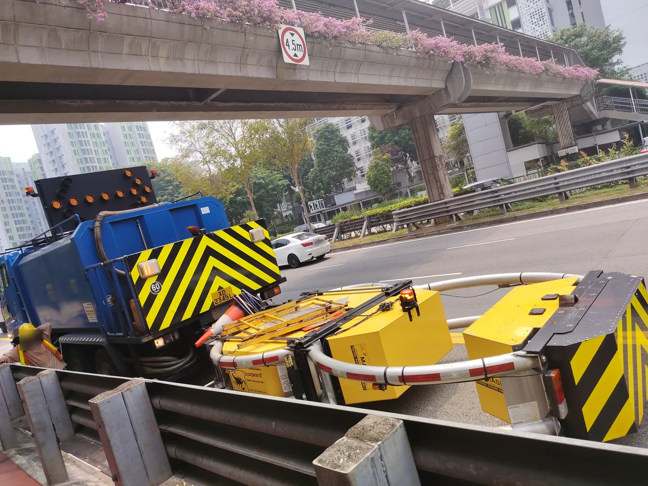 A blue work truck has a lit arrow board and a yellow impact cushion behind it.