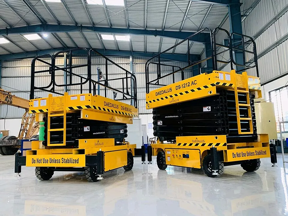 Two yellow scissor lifts have black guard rails around their platforms.
