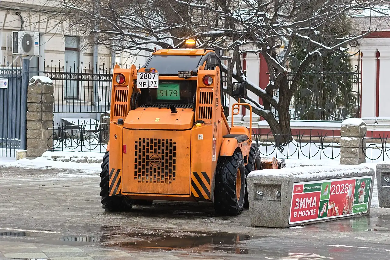 The back of an orange skid-steer loader has lights and a large grille.