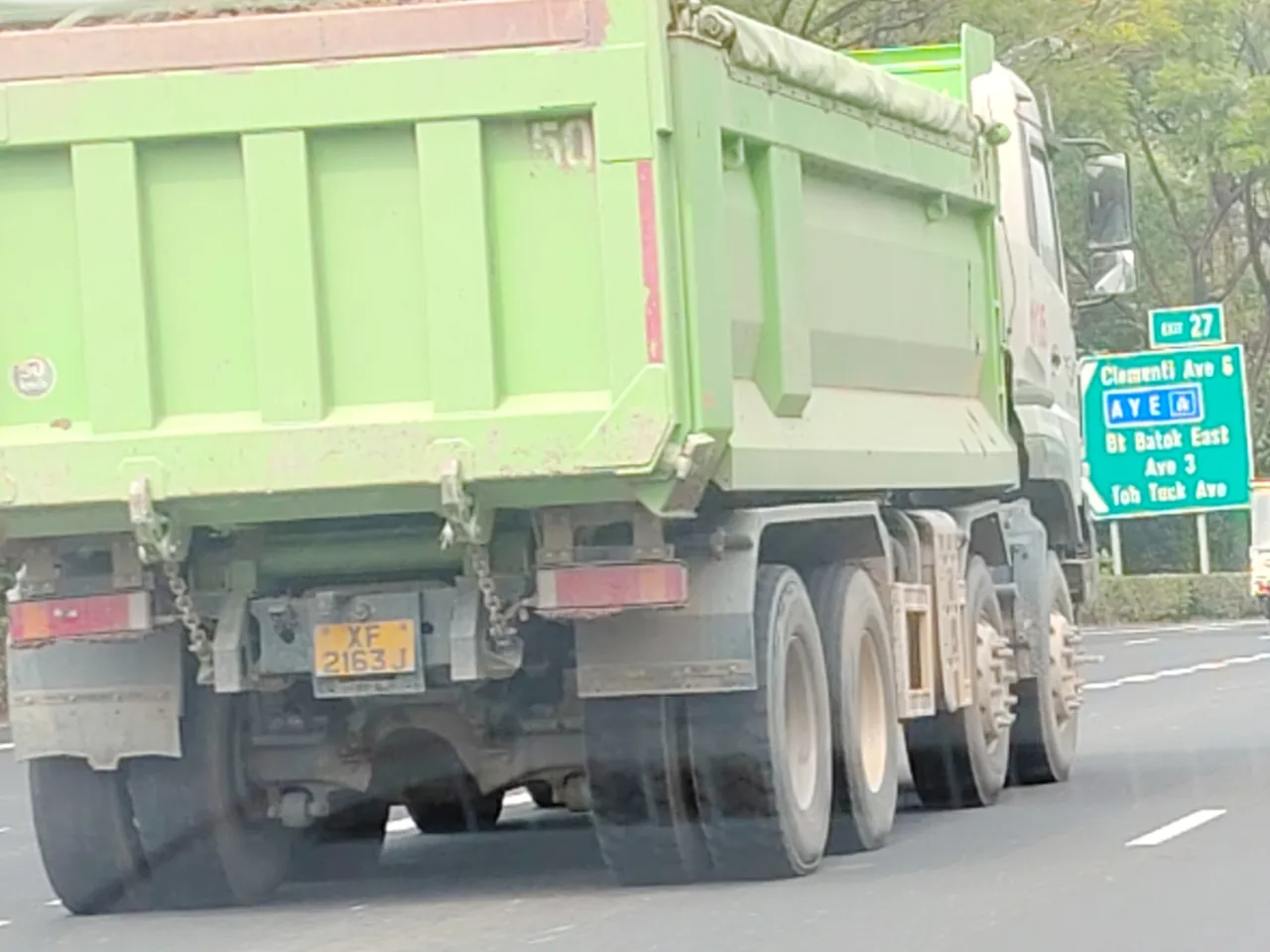 Tipper truck — the back of a green tipper truck with a full load, driving on the road, Photographed in Singapore