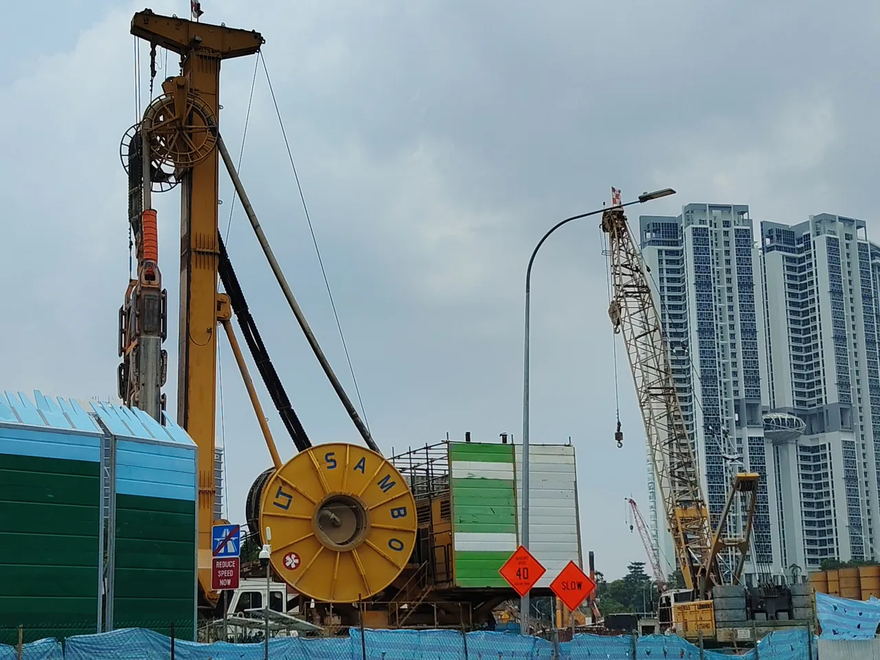 Trench cutter — a tall yellow machine with a high mast and a big yellow reel at a construction site, Photographed in Singapore