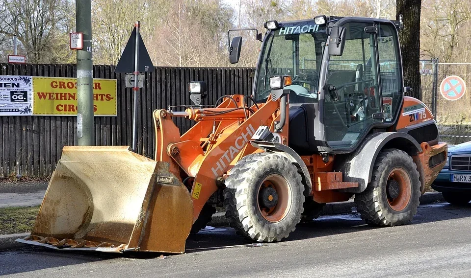An orange wheel loader has a broad bucket and four large tyres.