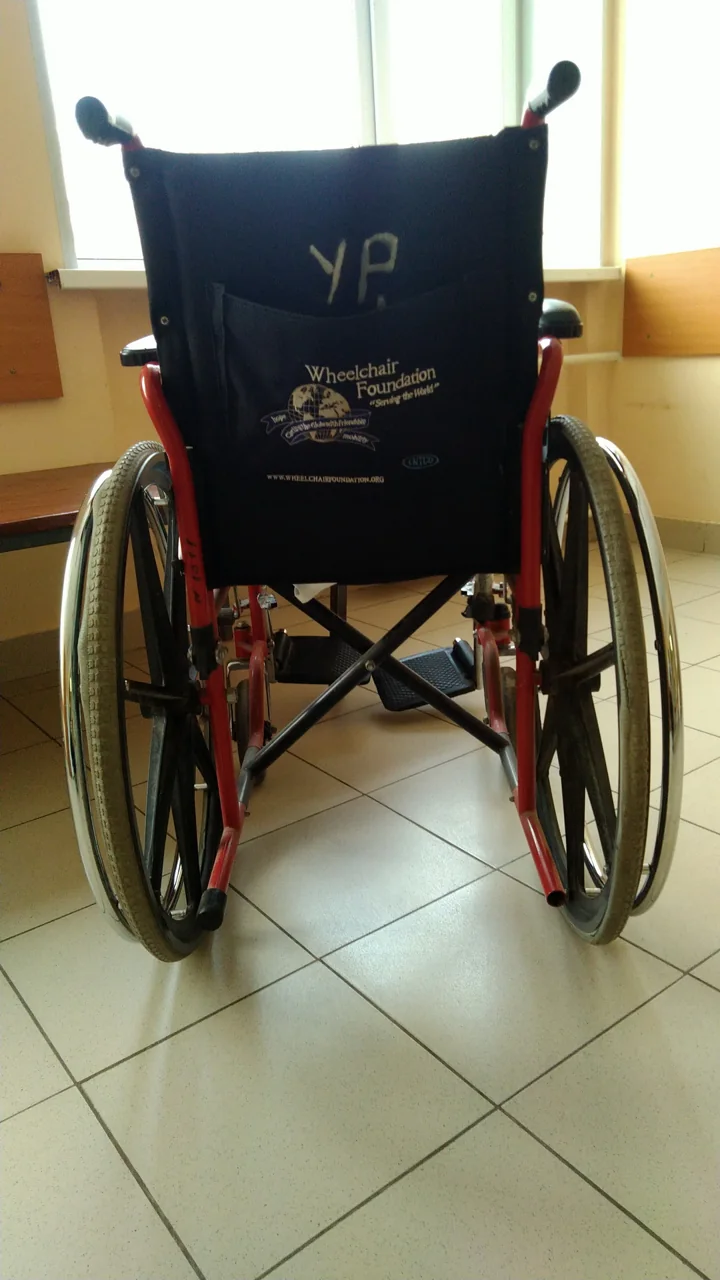 A wheelchair seen from behind has two large wheels and push handles.
