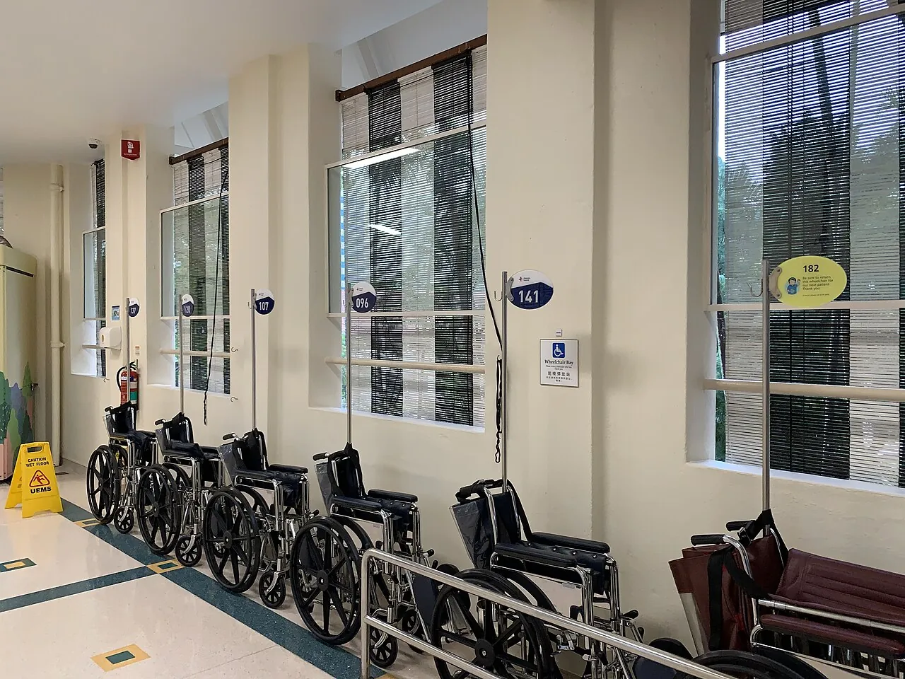 Several black wheelchairs are lined up indoors.