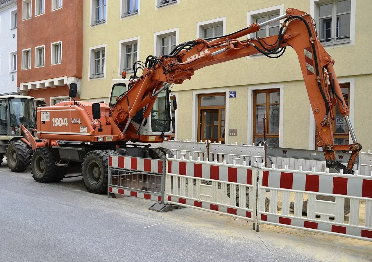 An orange excavator on rubber tyres beside roadworks in Germany.